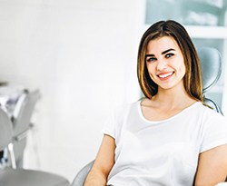 Woman in whit shirt smiling while sitting in dental office