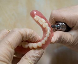 Lab technician filing dentures 