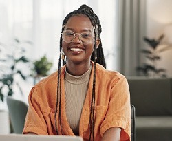 Woman with glasses smiling while working on laptop