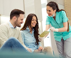 Dental assistant showing smiling couple form
