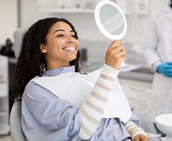 Woman smiling at reflection in handheld mirror