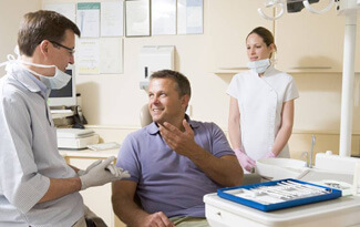 Man in dental chair talking to dentist