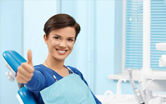 Smiling woman in dental chair giving thumbs up