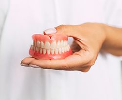 Woman holding full dentures