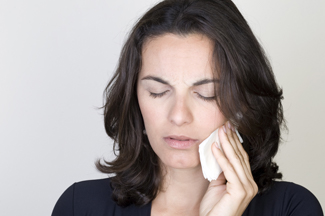 Woman holding cold compress to cheek