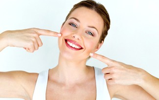 Young woman pointing to smile after teeth whitening in Lincoln.