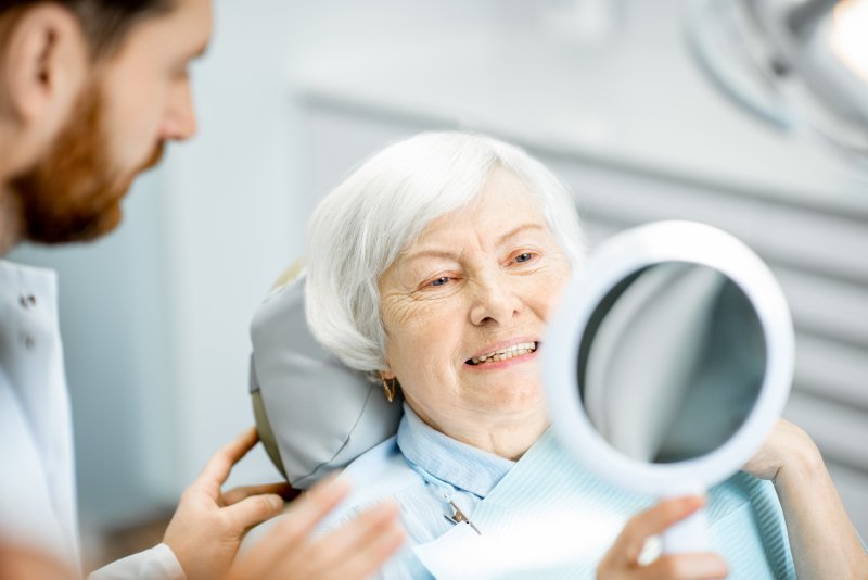 an older lady in the dentist chair looking at her smile