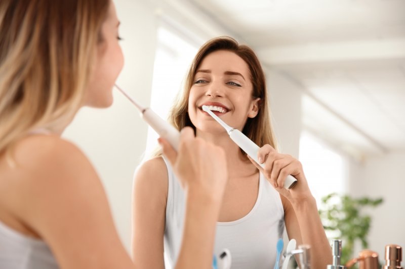 Adult woman brushing teeth with electric toothbrush