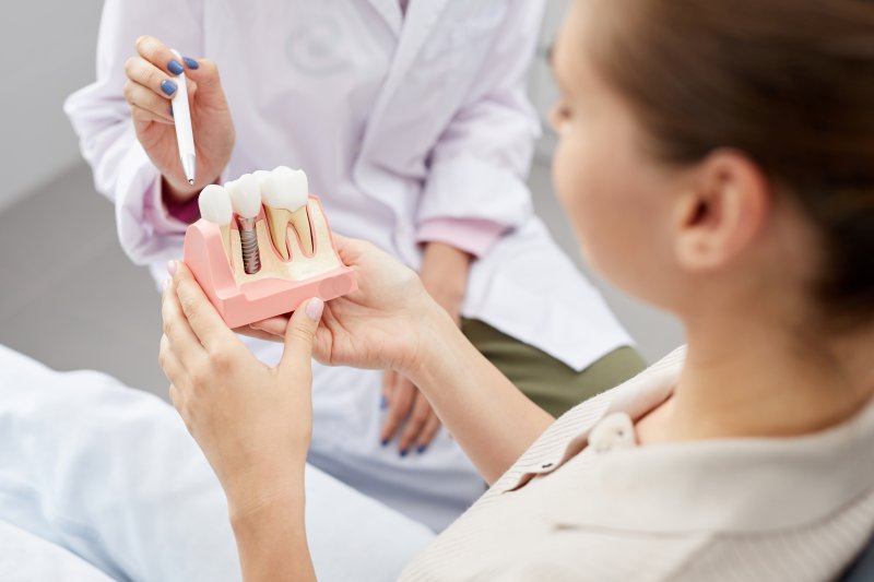 Dentist showing an implant model to a patient
