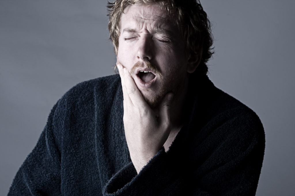 A man holding his jaw due to an impacted wisdom tooth