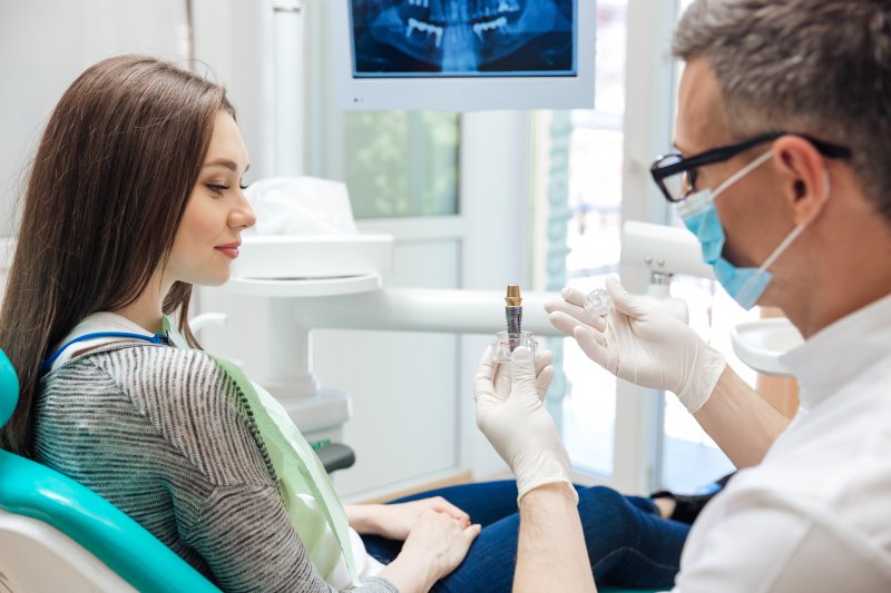 A male dentist showing his patient how a dental implant works