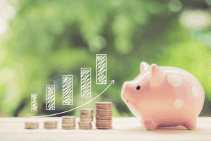 Increasingly larger stacks of coins next to a pink piggy bank